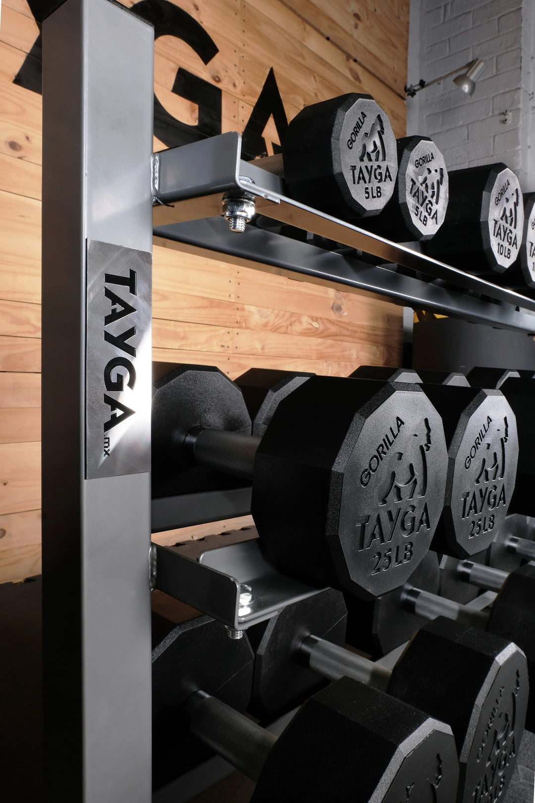 Pesas hexagonales Tayga en soporte metálico, gimnasio con pared de madera y ladrillo